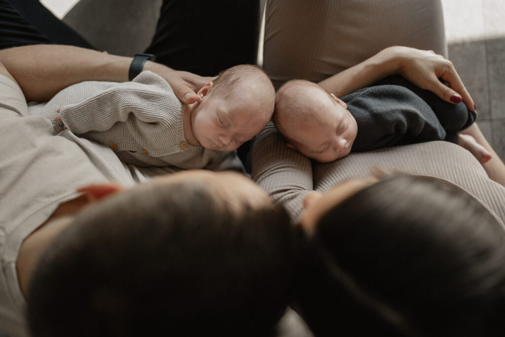 zwei Babys schlafen in den armen der Eltern